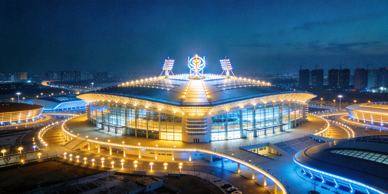 大型综合性体育中心夜景，灯光璀璨，建筑现代